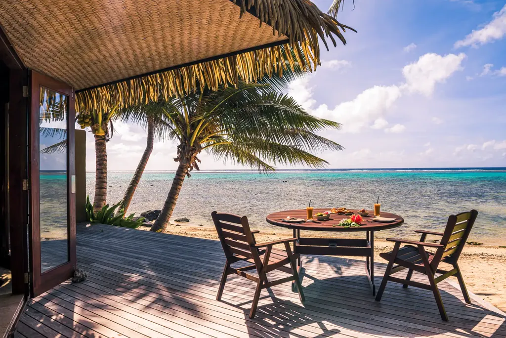 Holzdeck-Terrasse mit Tisch und Stühlen zum Strand